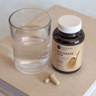 Fenugreek seed supplement bottle with water glass and capsules on a neutral background for health promotion.
