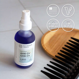 Hair Elixir PRO bottle on tile with comb, labeled as lab tested, vegan, and made in USA.