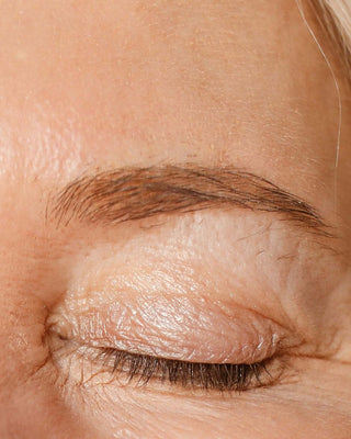 Close-up of mature woman's closed eye and silver hair, symbolizing graceful aging and skincare focus for longevity.