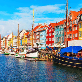 Colorful waterfront buildings and boats in Nyhavn, Copenhagen, under a bright blue sky.