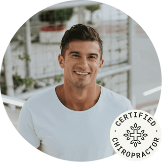 Smiling certified chiropractor in a casual white shirt, promoting health and wellness.