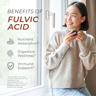 Smiling woman drinking from a cup by the window with Fulvic Acid benefits: digestion, and immune support.