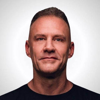 Headshot of a man with short hair and a neutral expression on a simple background.