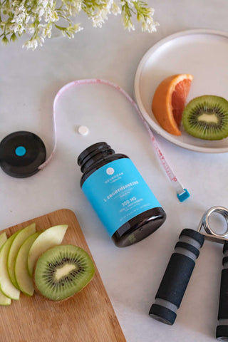 Healthy lifestyle setup with vitamins, green apple slices, kiwi, and fitness gear on a table.