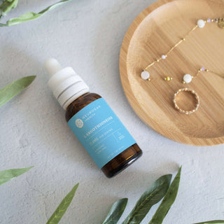 Neurogan L-Glutathione liquid supplement bottle alongside jewelry on a wooden plate with greenery.