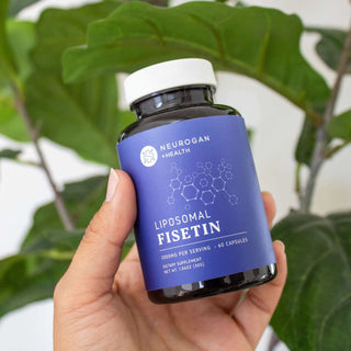 Person holding a bottle of Neurogan Health Liposomal Fisetin dietary supplement with green leaves in the background.