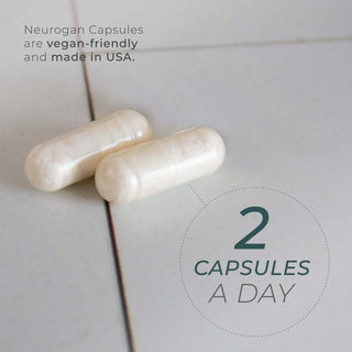 Two white NAD+ Resveratrol capsules on a tiled surface with label text suggesting a serving of two capsules daily