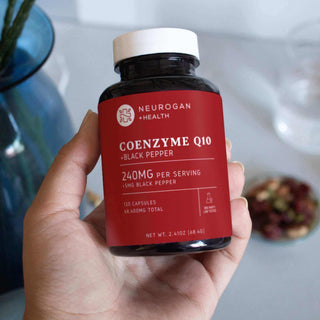 Coenzyme Q10 supplement bottle with black pepper, 240mg, 120 capsules in a hand, promoting health benefits.