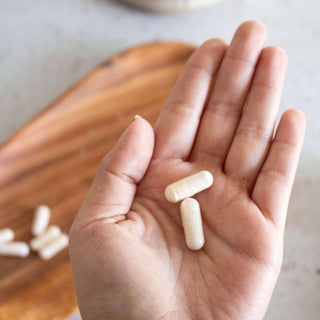 Hand holding NMN Capsules with additional capsules in the background.