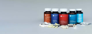Assorted supplement bottles with pills on a gray background, showcasing health and wellness products.