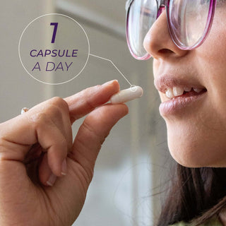 Woman holding a white NMN capsule near her mouth with dosage guide, one capsule per day
