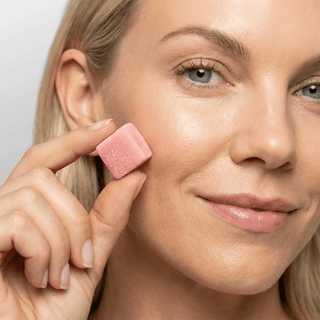 Urolithin A Gummies in hand of a smiling woman, showcasing the strawberry-flavored gummy perfect for daily wellness.