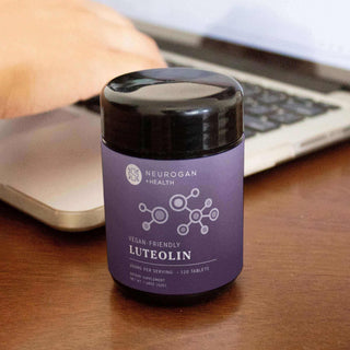 Vegan-friendly Luteolin supplement in a black container placed on a wooden table next to a laptop.
