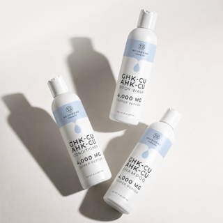 GHK-Cu + AHK-Cu shampoo, conditioner and body wash bottles flat lay