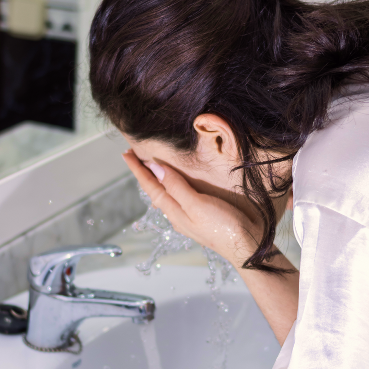 Rinsing the face with water over a bathroom sink