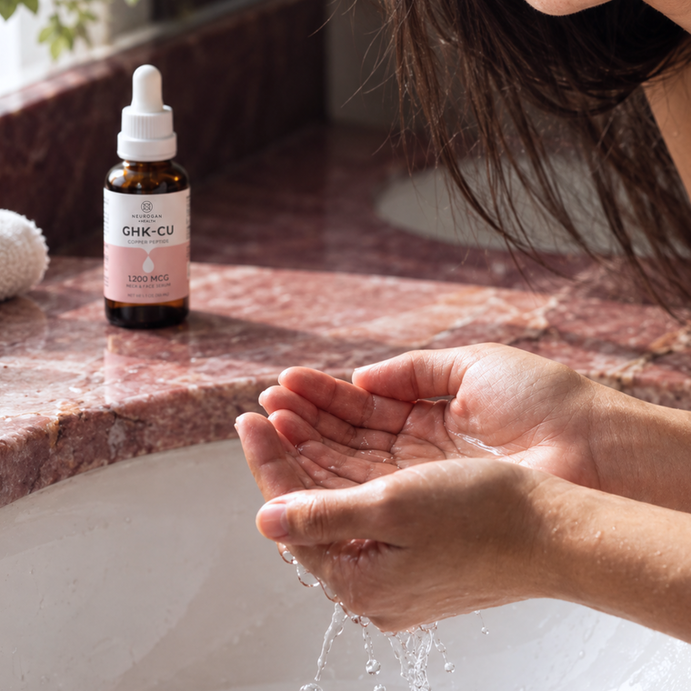 Hands cupping water over a washbasin