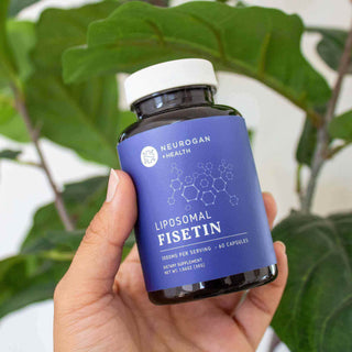 Person holding a bottle of Neurogan Health Liposomal Fisetin dietary supplement with green leaves in the background.