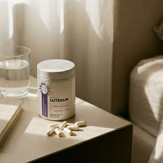 Liposomal Luteolin 100mg tablets in a bottle on a bedside table with a glass of water.