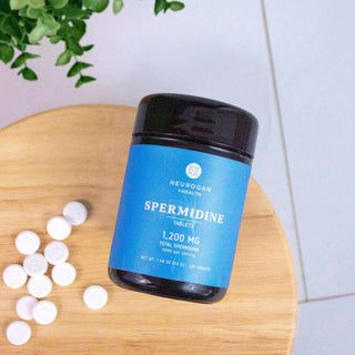 Neurogan Spermidine tablets in a blue container on a wooden surface with white tablets beside it.