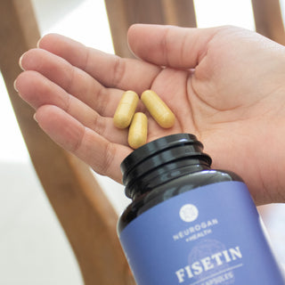 Fisetin Capsules - Blue-labeled bottle with yellow capsules poured into a hand.