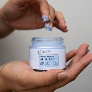 GHK-CU Face Cream 1,200 mg - Open jar with blue cream applied to fingers, in a 2 oz container.