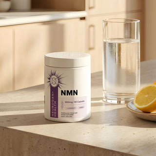 NMN Capsules 900mg bottle on a kitchen counter with a glass of water and lemon.