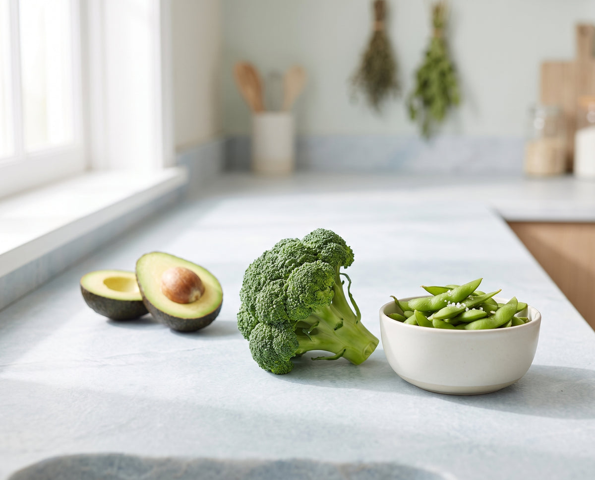 Broccoli, a bowl of edamame and a halved avocado on a bright kitchen counter