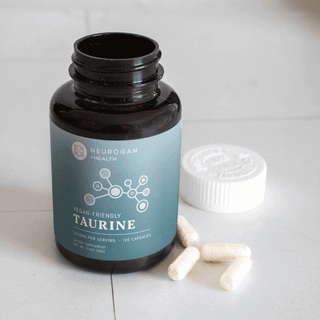 Vegan-friendly Taurine supplement bottle with capsules on table for health support from Neurogan.